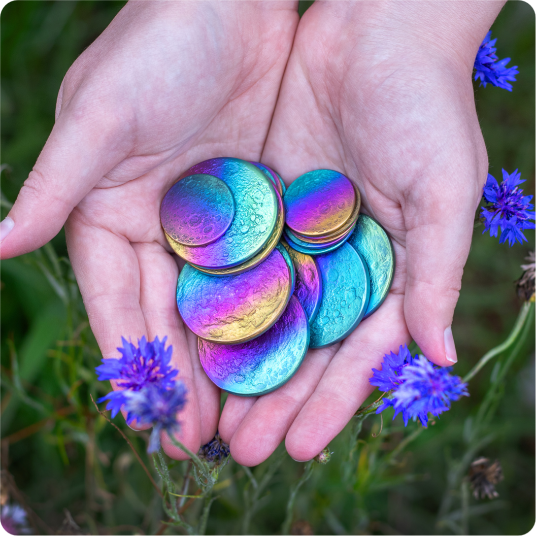 Hands holding Niobium Rainbow Moon Coins
