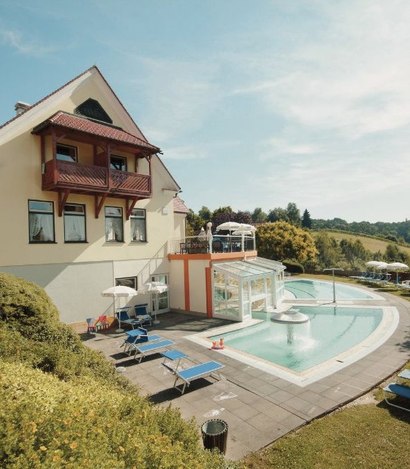 Hotel Außenansicht mit Pool, Liegen und Sonnenschirmen