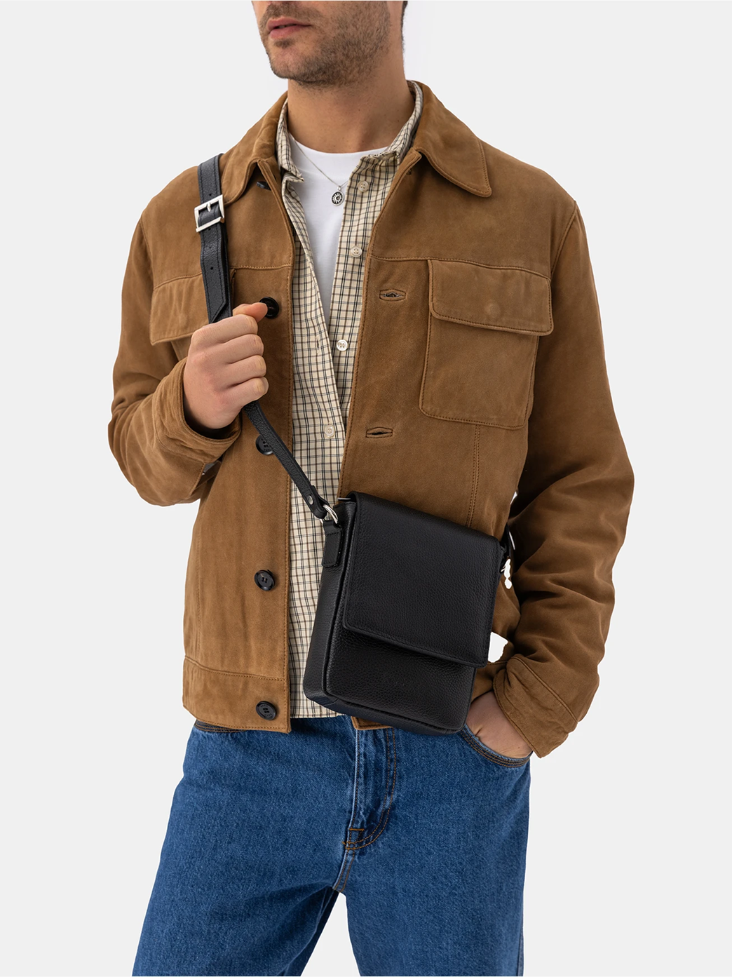 Man in brown jacket and jeans carrying a black leather crossbody bag