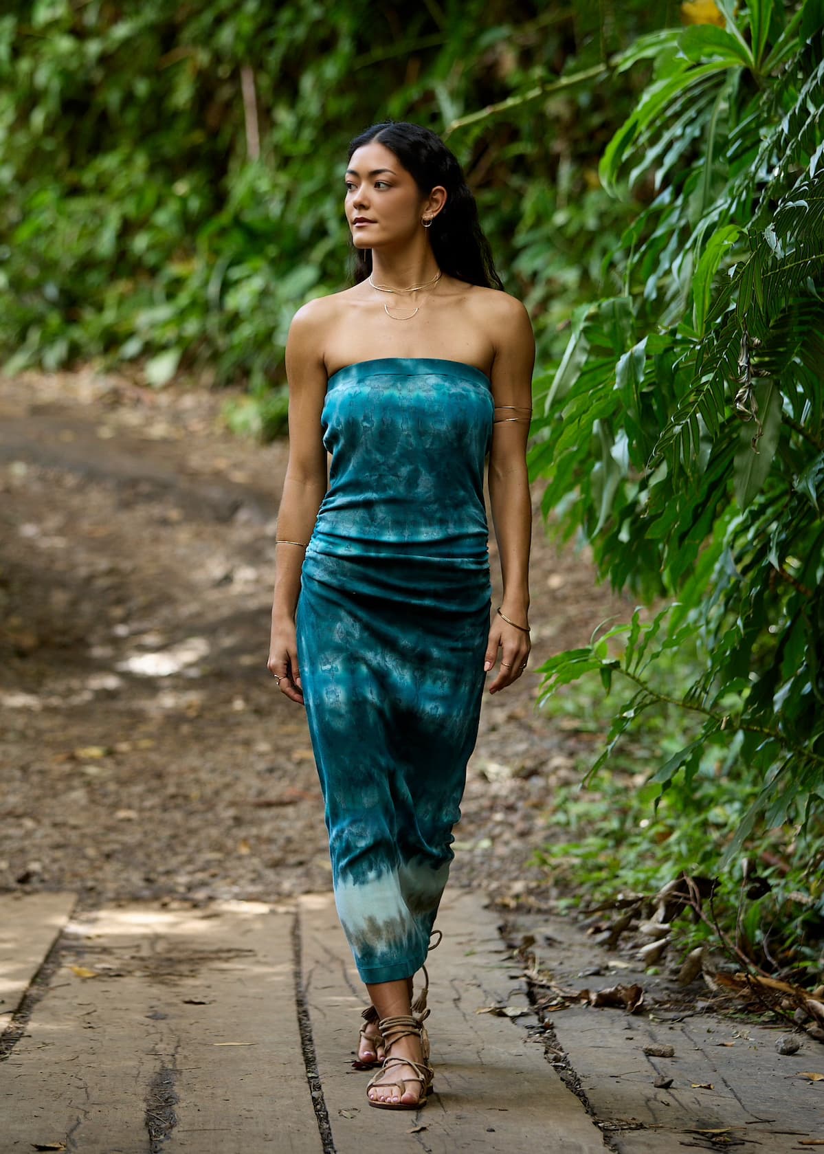Women wearing a long turquoise dress walking in the woods