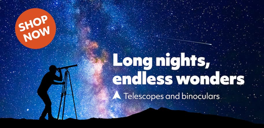 man using telescope with milky way in background