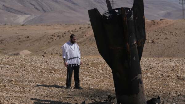 A man looks at the wreckage of an Iranian missile that landed near the West Bank city of Jericho.