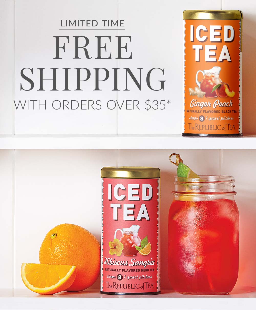 Tin of Ginger Peach Iced Tea and Hibiscus Sangria Iced Tea with an iced tea glass and a whole orange with an orange slice next to the hibiscus Sangria tin on a kitchen cabinet shelf