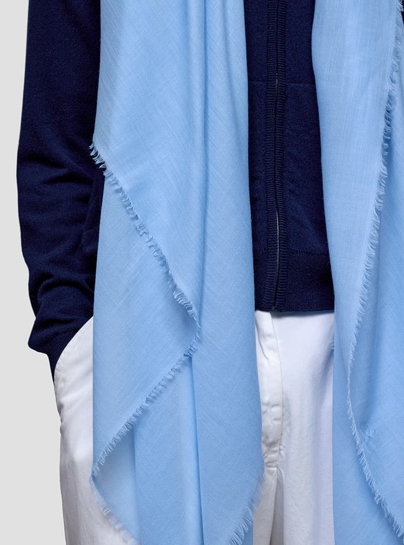 close up of someone wearing a light blue cashmere scarf and navy hoodie