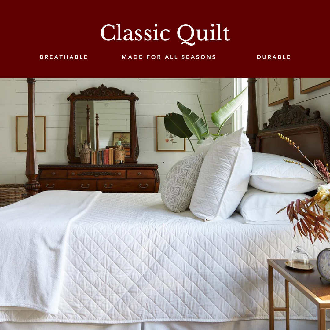 A well-made bed in a traditionally decorated bedroom, featuring a white diamond-quilted coverlet and a red banner overhead.