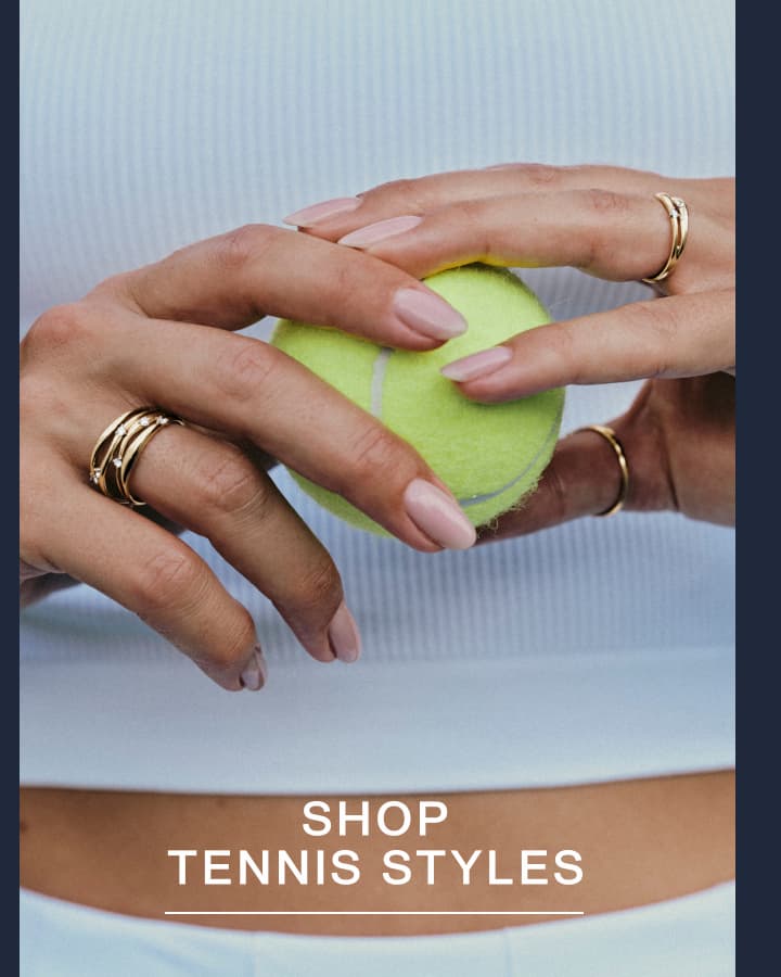 Hands holding a tennis ball wearing stacked Mejuri gold rings — Shop Tennis Styles.