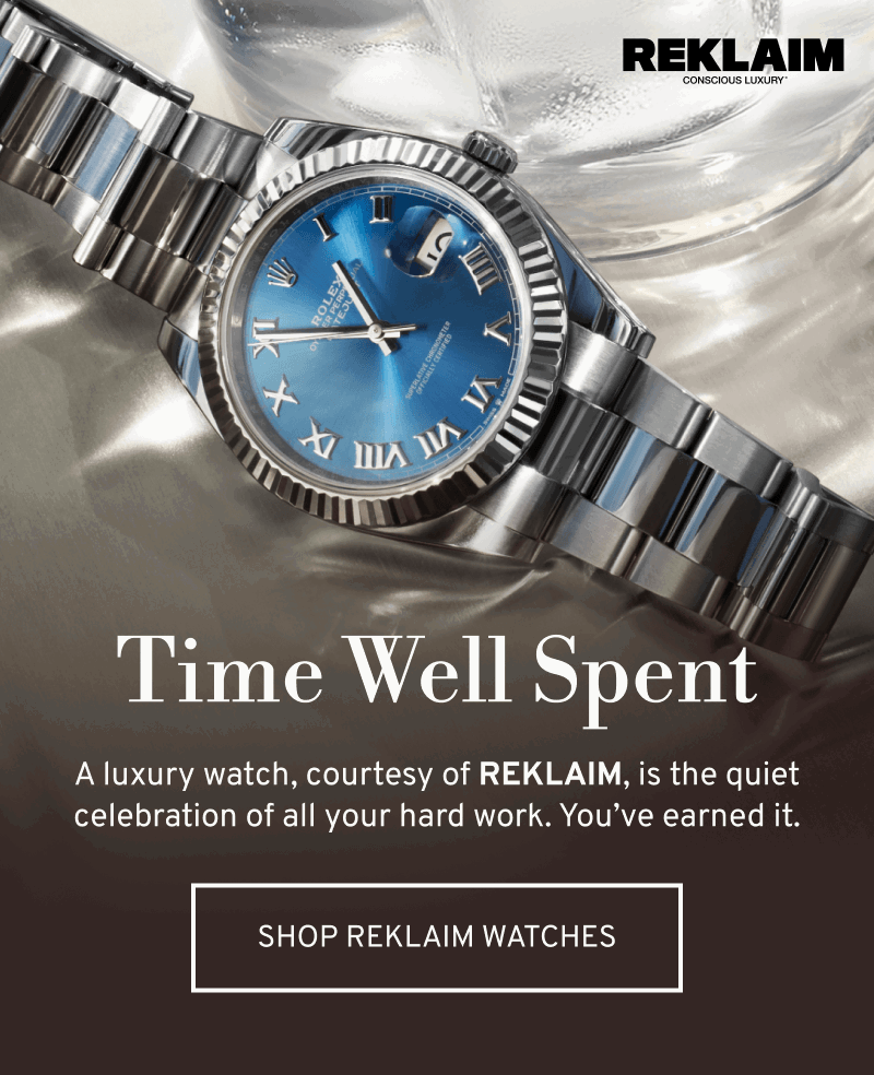 Stainless steel luxury watch with blue dial on reflective surface. Time Well Spent. Click to Shop REKLAIM Watches