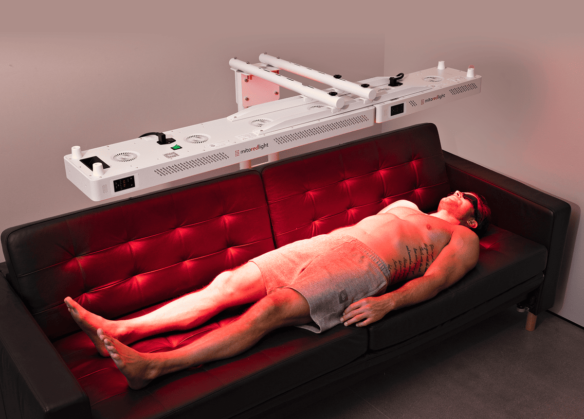 Man does red light therapy laying on couch.