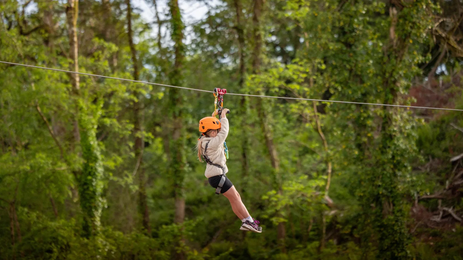 Girl going down the steep ravine summit flight zip line