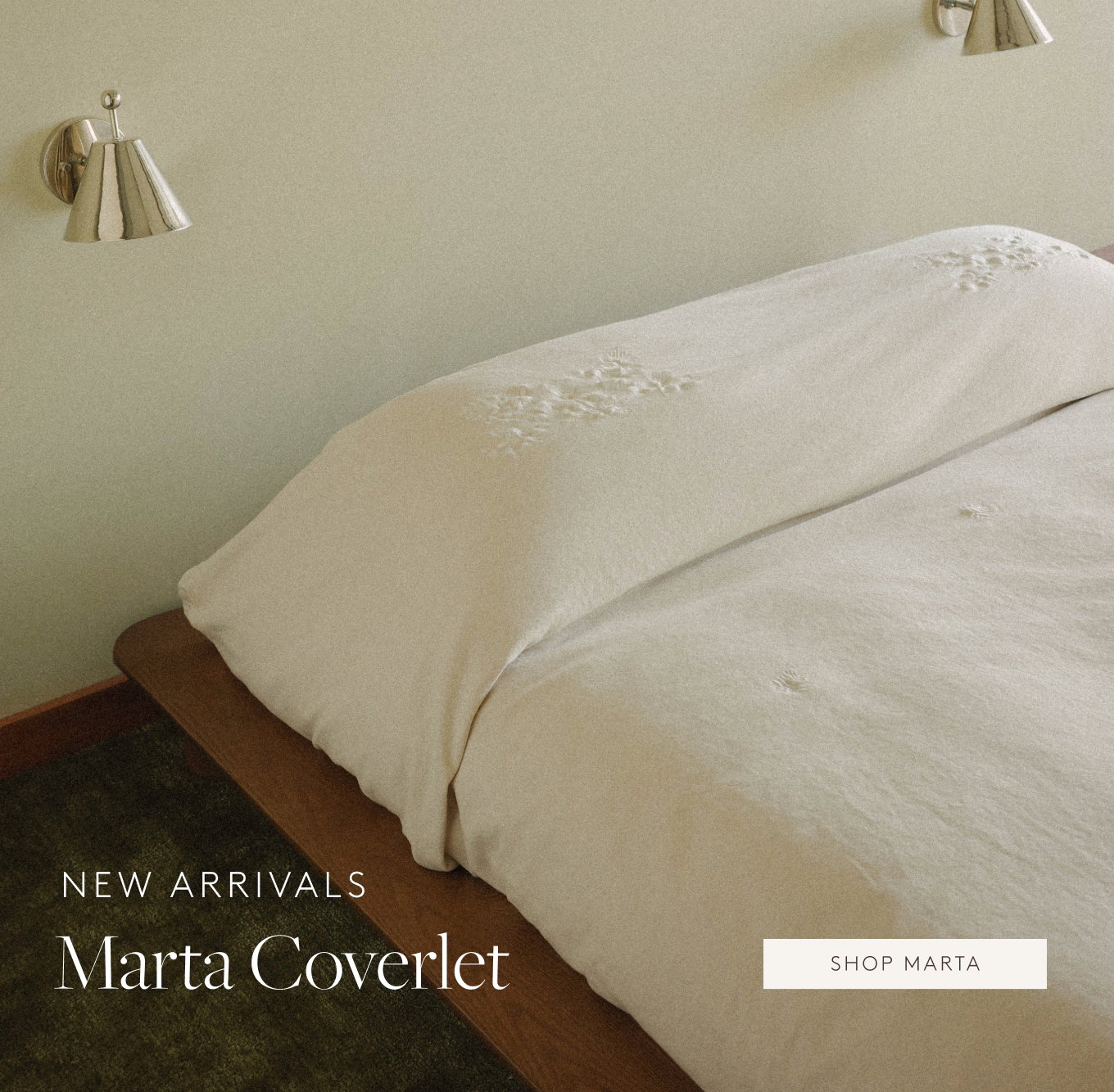 White floral embroidered blanket tucked into a wooden bed frame