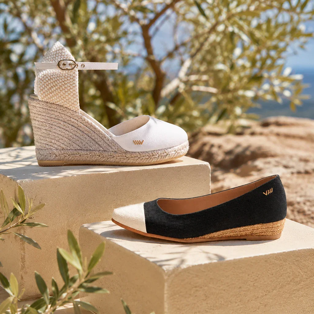 Viscata shoes displayed on sandy platforms with olive trees and Mediterranean coastline in background