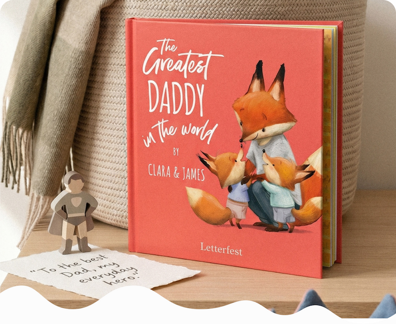  personalised "The Greatest Daddy in the World" book with an illustrated fox family on the cover, displayed with a small superhero figure and a handwritten note