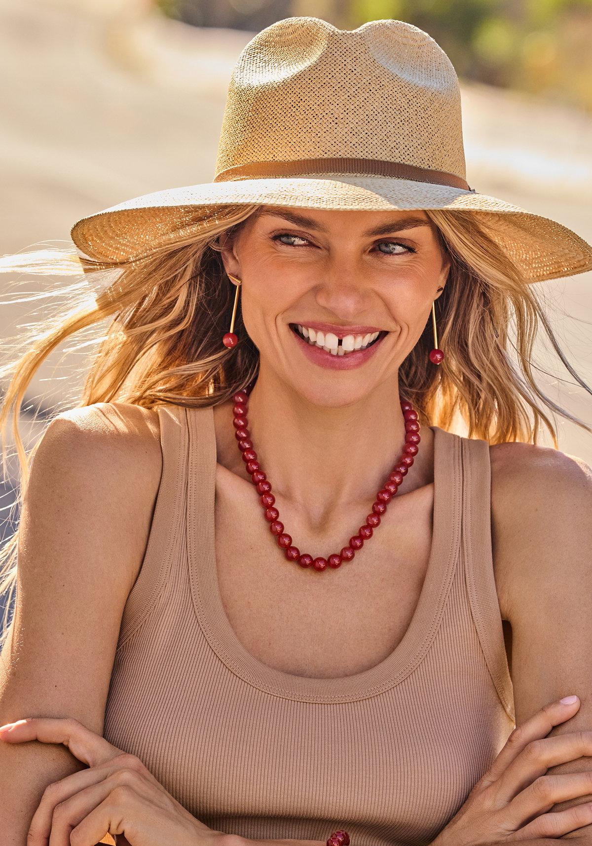 The Fiesta Capsule Packable Wide Brim Ecuador Hat in Dark Natural, Cerise Beaded Necklace in Carnelian Red, Cerise Bar Jacket Earrings in Carnelian Red. 