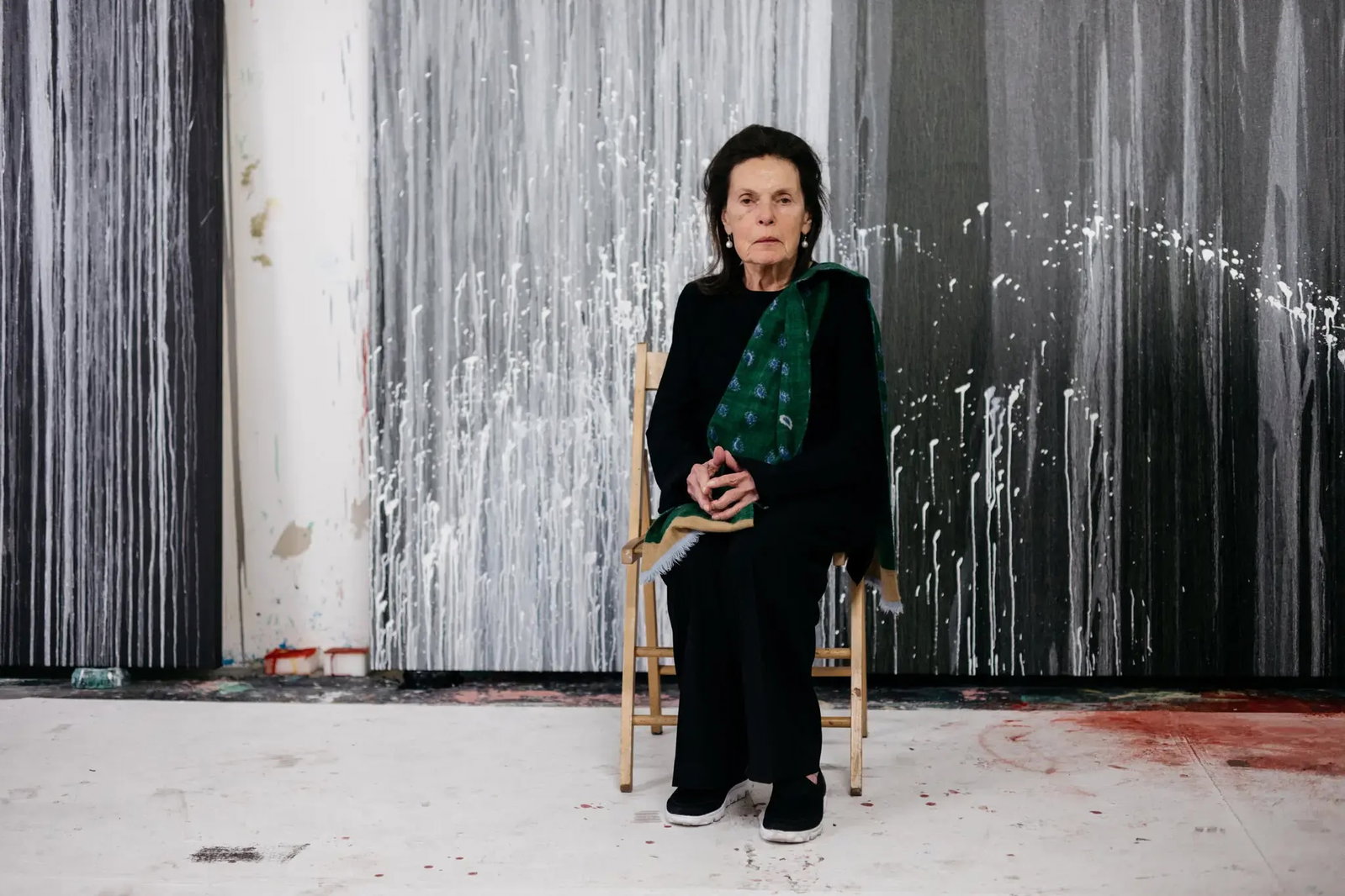 Pat Steir in her studio, seated before her poured paintings