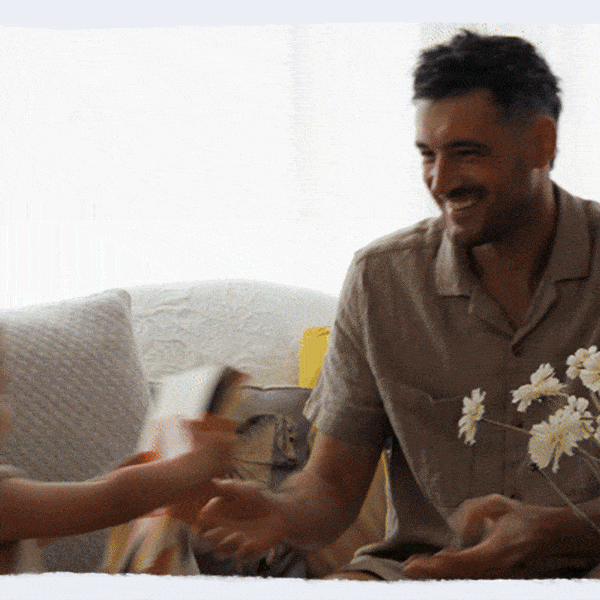 Father smiling as he receives a Father's Day gift and card from his child at home