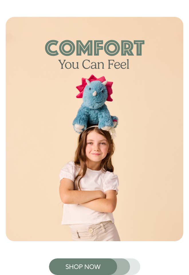 A little girl balancing Triceratops Warmies on her head. Shop Now.