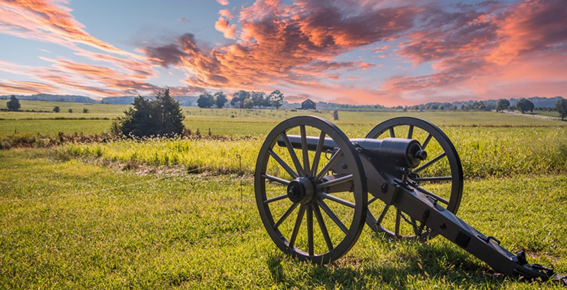 An old cannon aiming at a battlefield of Gettysburg.