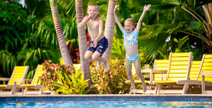 Two kids jumping into a pool. 