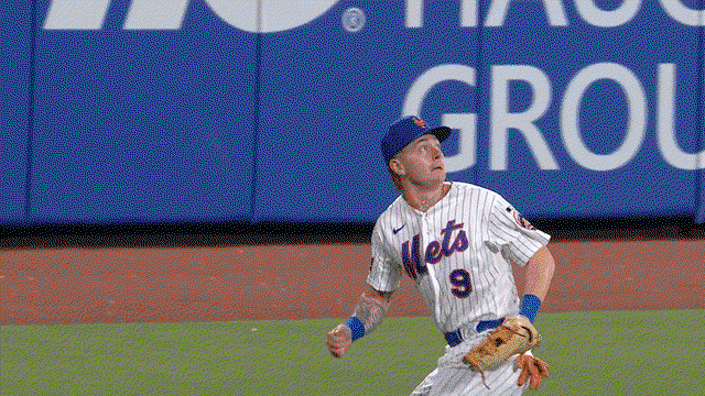 An animated gif of A.J. Ewing twisting around to make a catch in deep center field