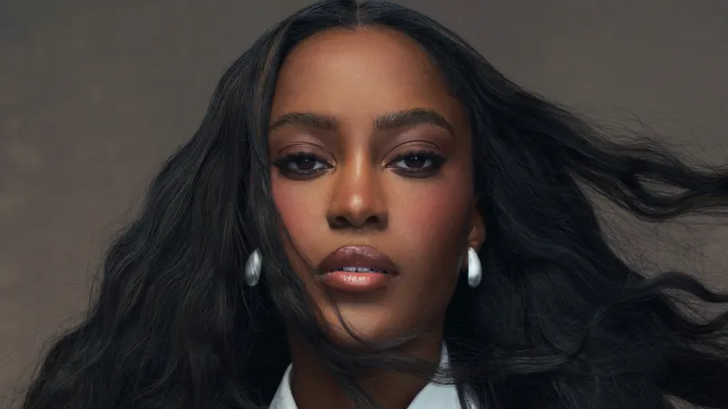 Ciara Miller wears a white shirt and tie. Her hair is styled in waves.