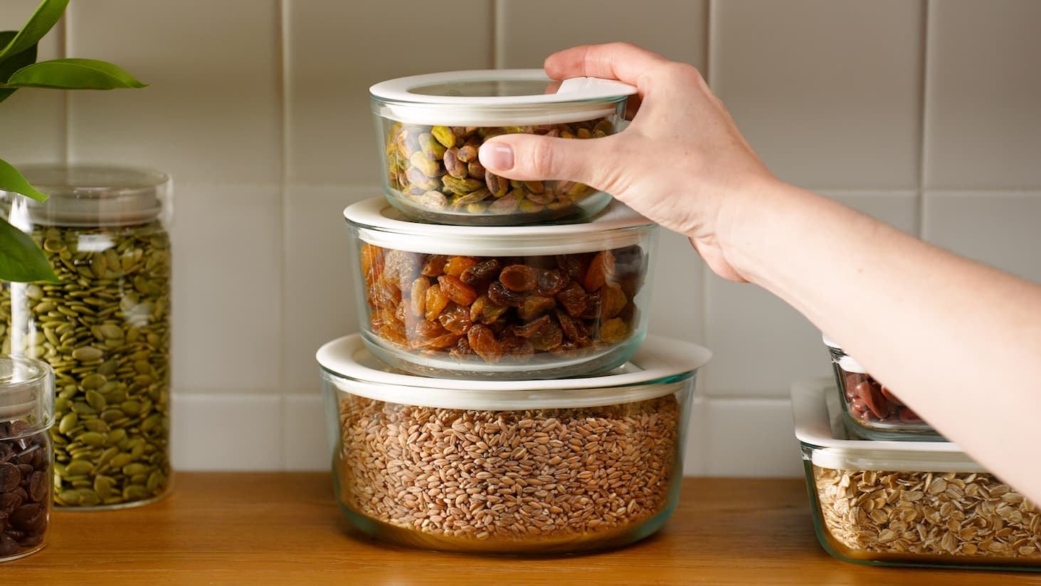 Stackable glass containers filled with dry foods on a kitchen counter.