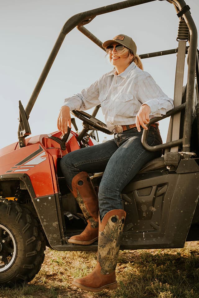 A woman wearing the Rush Strike 17" Snake Resisting Boot in Russett (Brown).