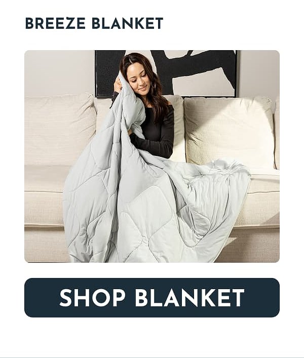 A woman sitting on a couch, holding a light gray blanket.