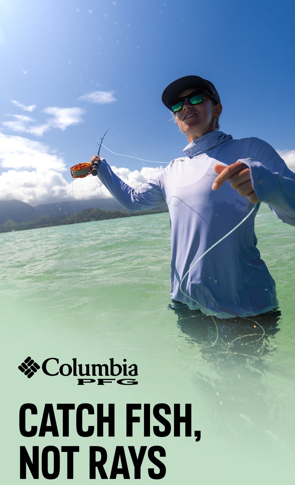 Headline: Catch Fish, Not Rays.A woman waist deep in the water, pulling on her fishing line while wearing Columbia PFG. 