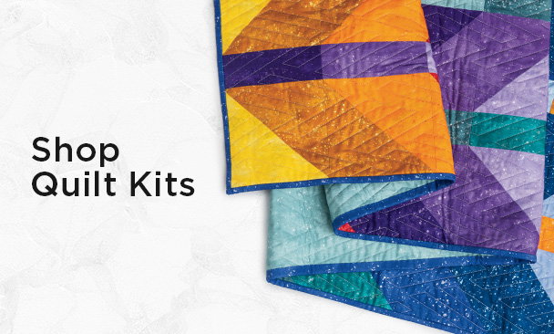 Text: Shop Quilt Kits Image: a colorful multi tonal quilt with modern chevron pattern