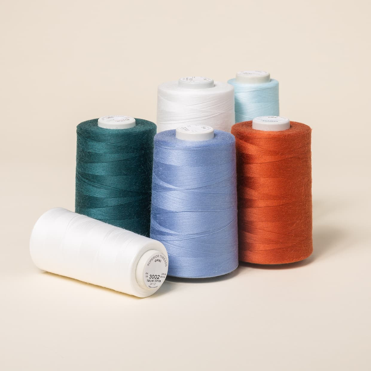 Six spools of sewing and quilting thread in blues, white, and red. >>