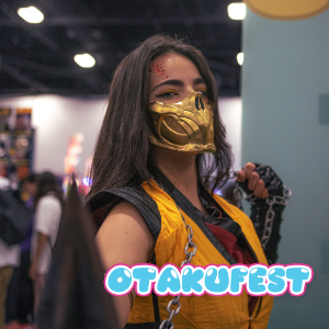 A cosplayer in a yellow and black costume poses indoors at a convention. The person holds a chain prop while standing in a crowded expo hall with blurred attendees in the background. The atmosphere is lively and colorful, with soft lighting and a playful graphic overlay. The word "OTAKUFEST" appears prominently in bright, bubble-style text at the bottom of the image.