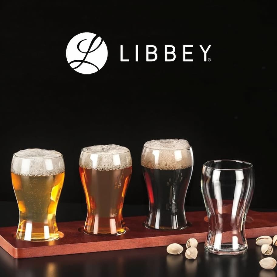 Libbey beer glass set displayed with multiple filled glasses in varying beer styles and one empty glass on a wooden serving board.