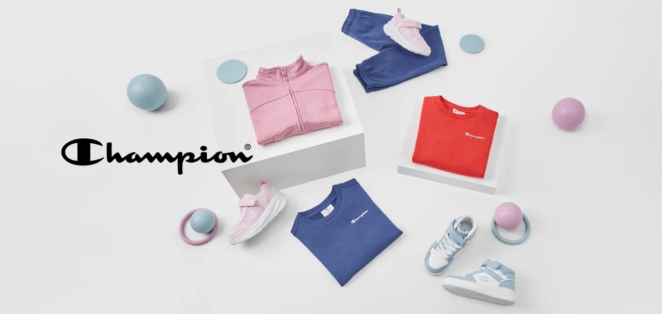 Vier Kleidungsstücke: eine rosa Zip-Jacke, ein rotes T-Shirt, ein blaues T-Shirt und marinefarbene Hosen. Zwei Paar Schuhe und bunte Bälle in der Nähe.