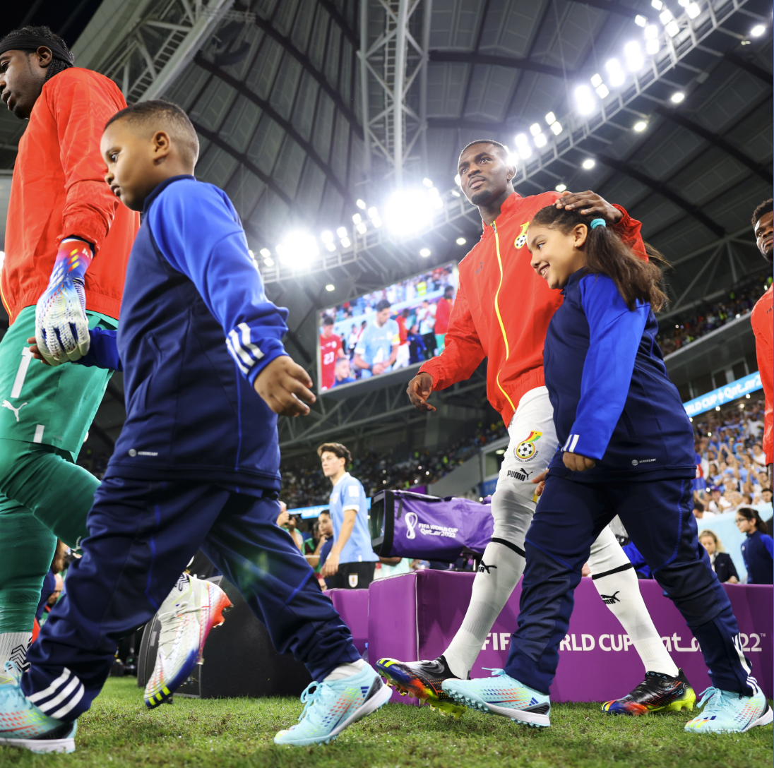 Photo of World Cup soccer players walking onto a field holding the hands of kids during pregame ceremonies 