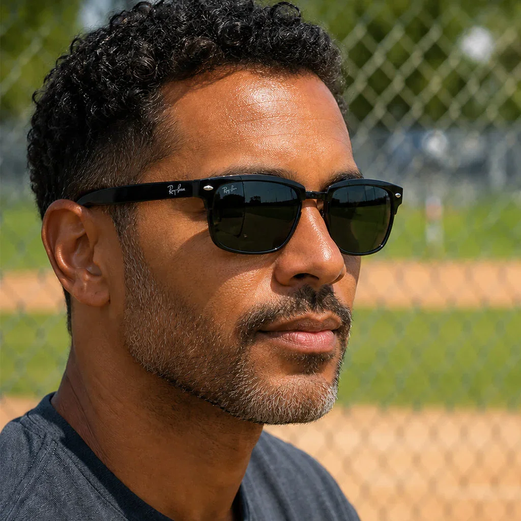 Man wearing black Ray-Ban sunglasses and blue shirt at baseball field