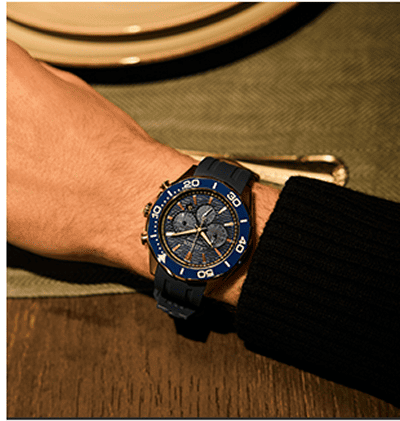 Close up of a navy chronograph watch worn on the wrist.