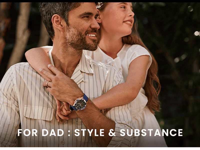 Father holding his daughter while wearing a blue chronograph watch.