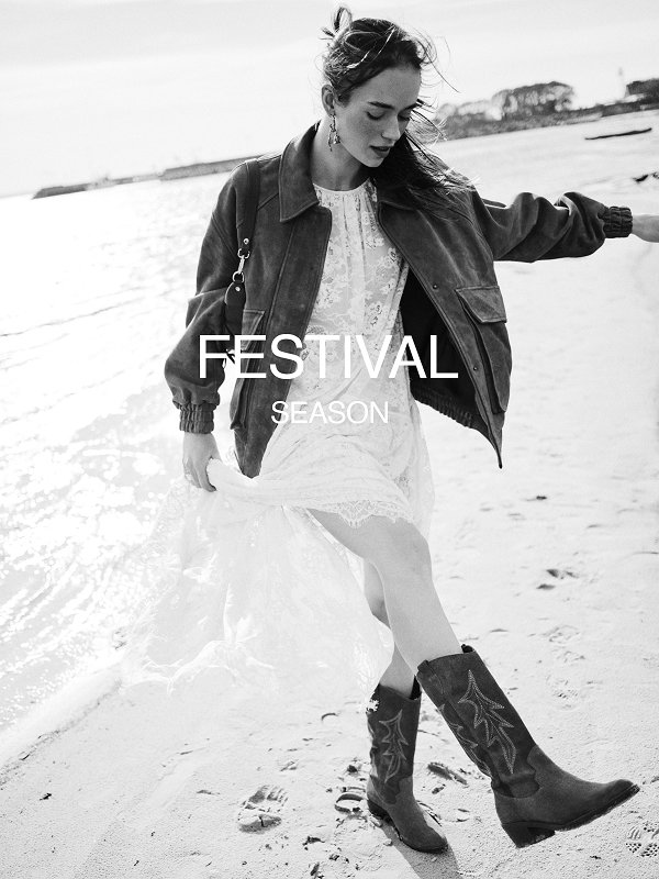 Woman in lace dress and boots walking on beach, festival season theme