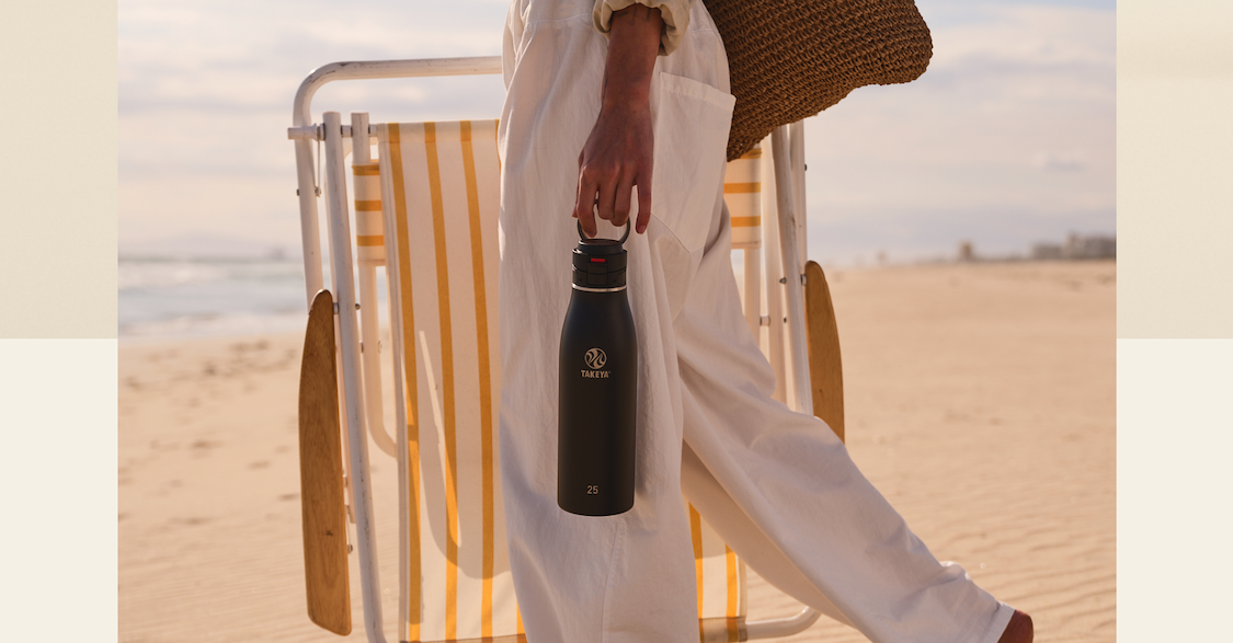 Black Takeya Traveler carried by the loop handle during a beach walk.