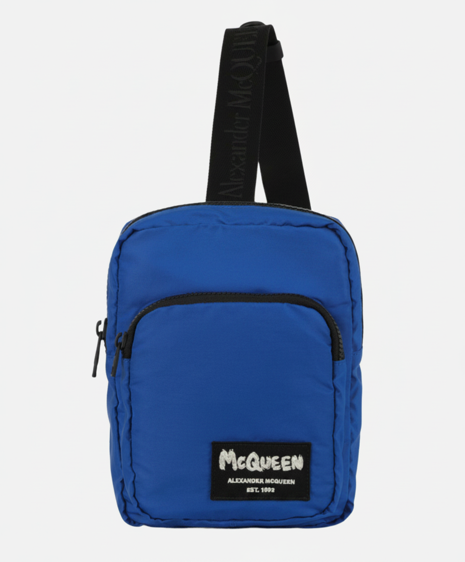 Blue Alexander McQueen crossbody bag with logo patch and branded strap.