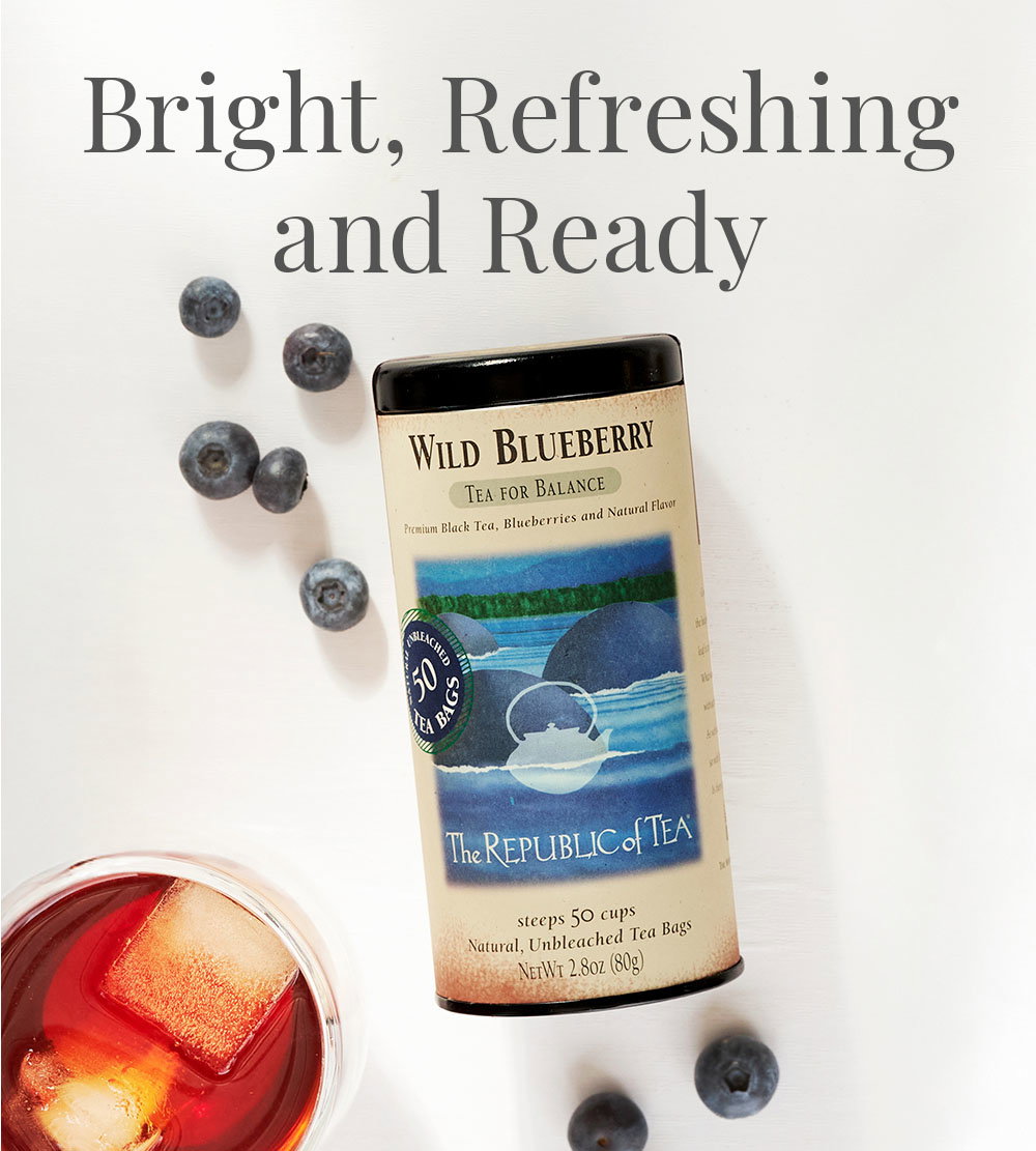 Overhead view of Wild Blueberry Tea Tin with blueberries surrounding it and with a cup of Iced Wild Blueberry tea next to tin