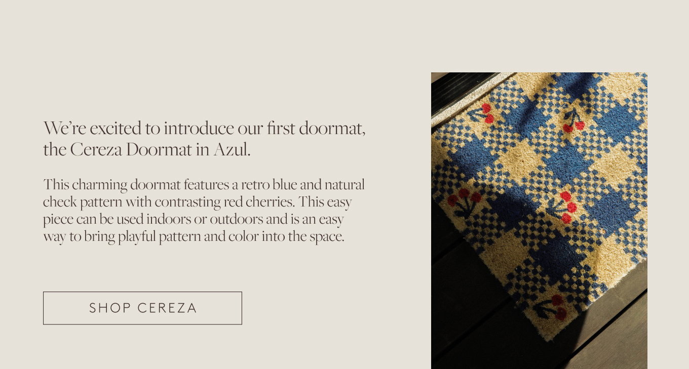 Detail of a blue and yellow checked doormat with a cherry pattern