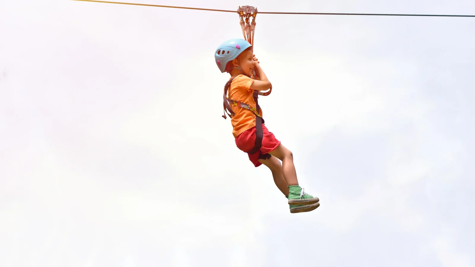 young lad soaring across steep ravine zipline