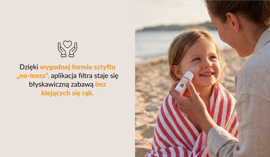 Parent applying sunscreen stick to smiling young girl wrapped in a striped towel on a sandy beach, sun protection for children