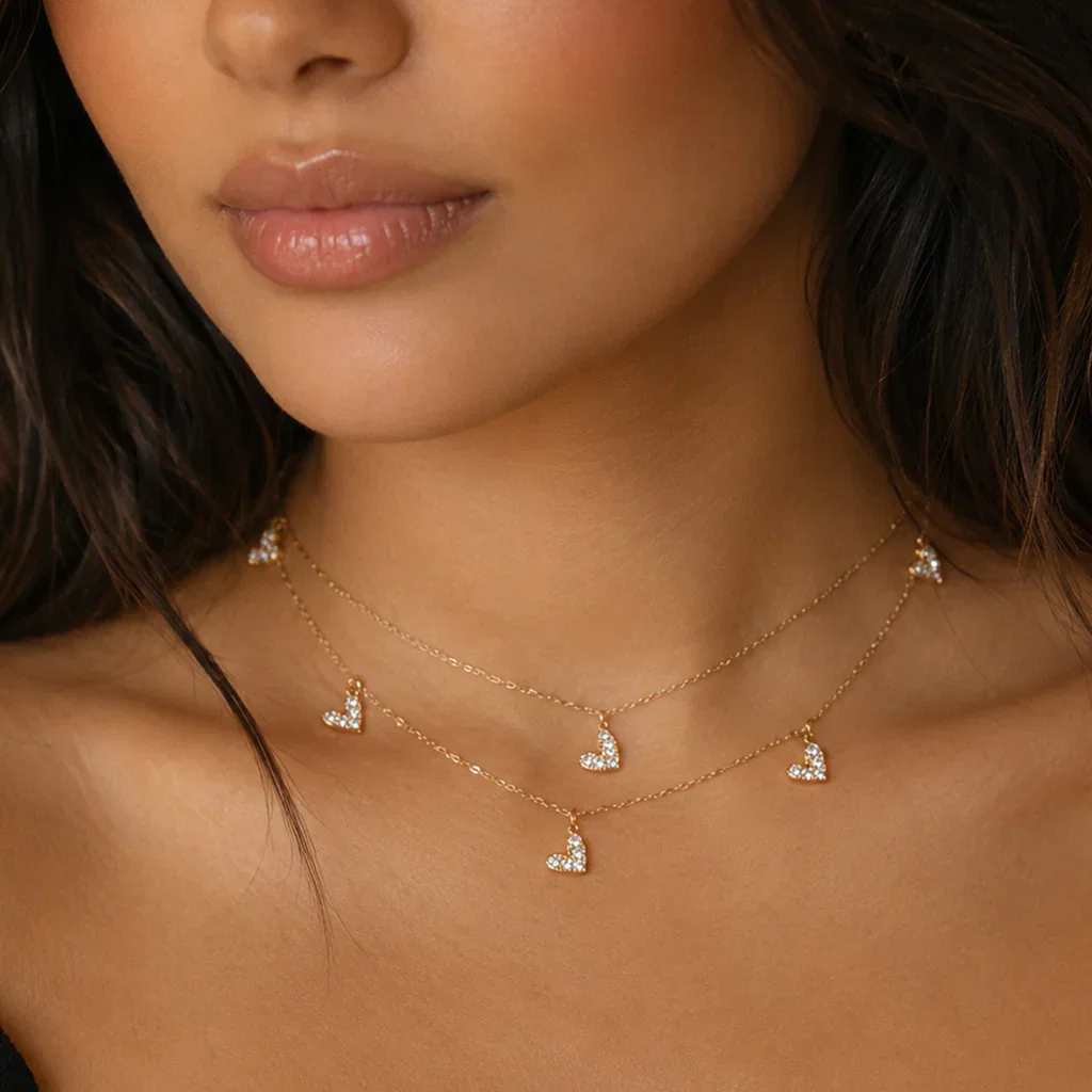 Woman wearing layered gold necklaces with diamond heart pendants from the Best of JewelsBySunaina collection