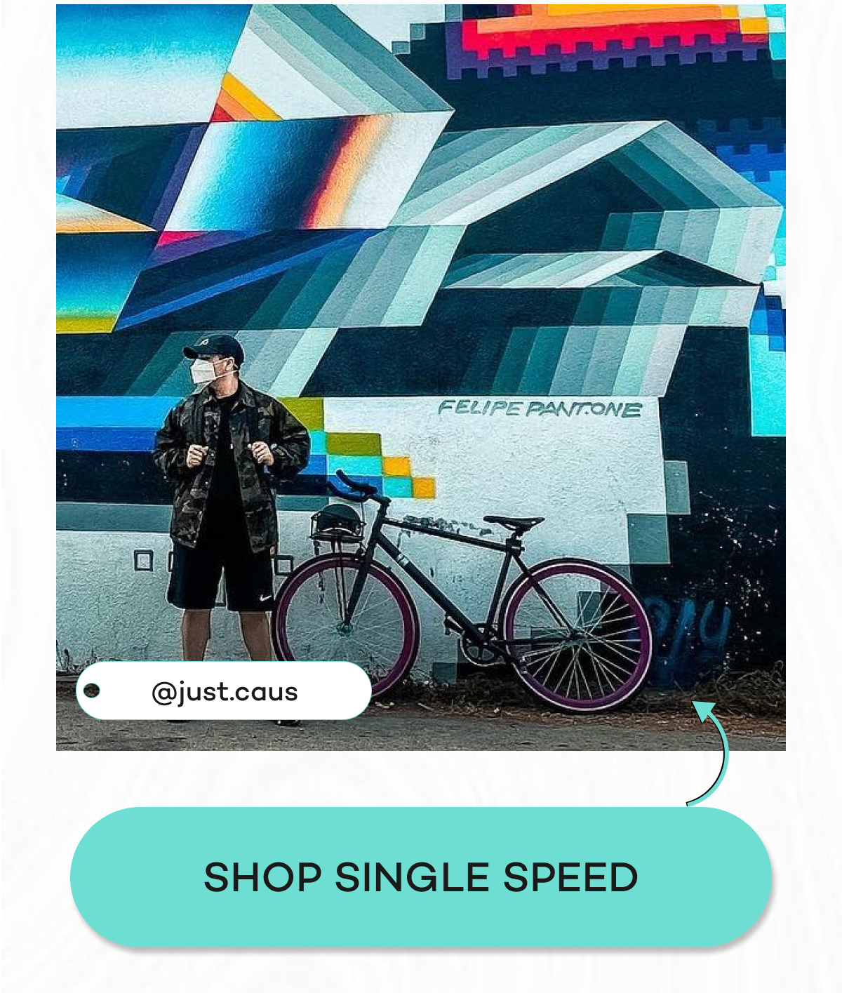 Person in a camo jacket stands next to a colorful mural with a Single speed bicycle.
