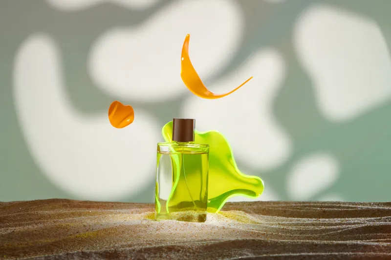 Photo of fragrance bottle with neon green blob and orange petals