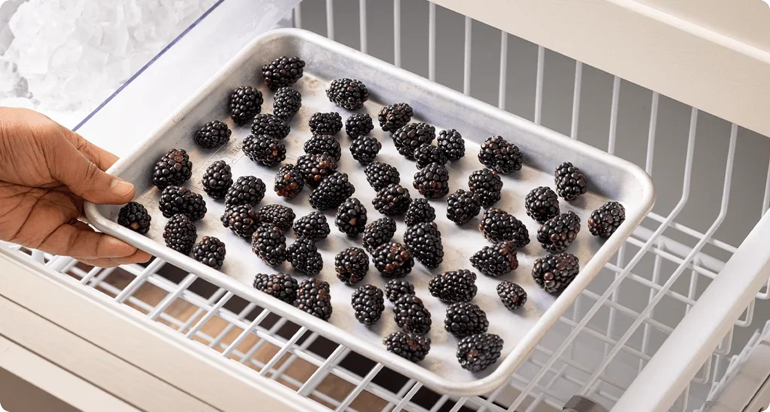 Placing berries on a sheet pan into the freezer
