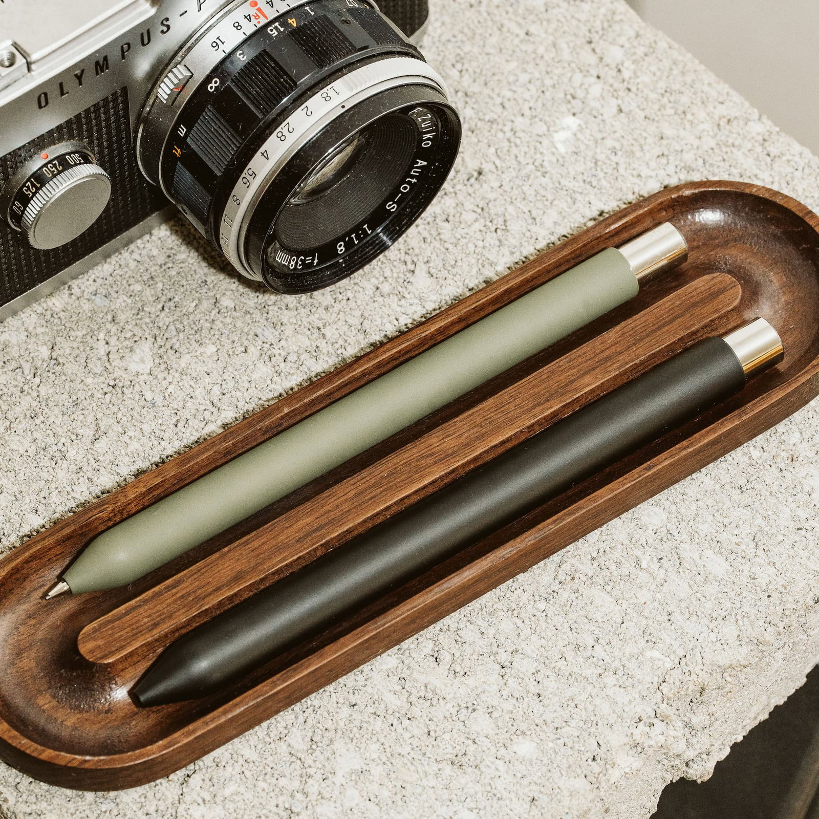 A black Mark One Steel on a walnut pen tray on a desk.