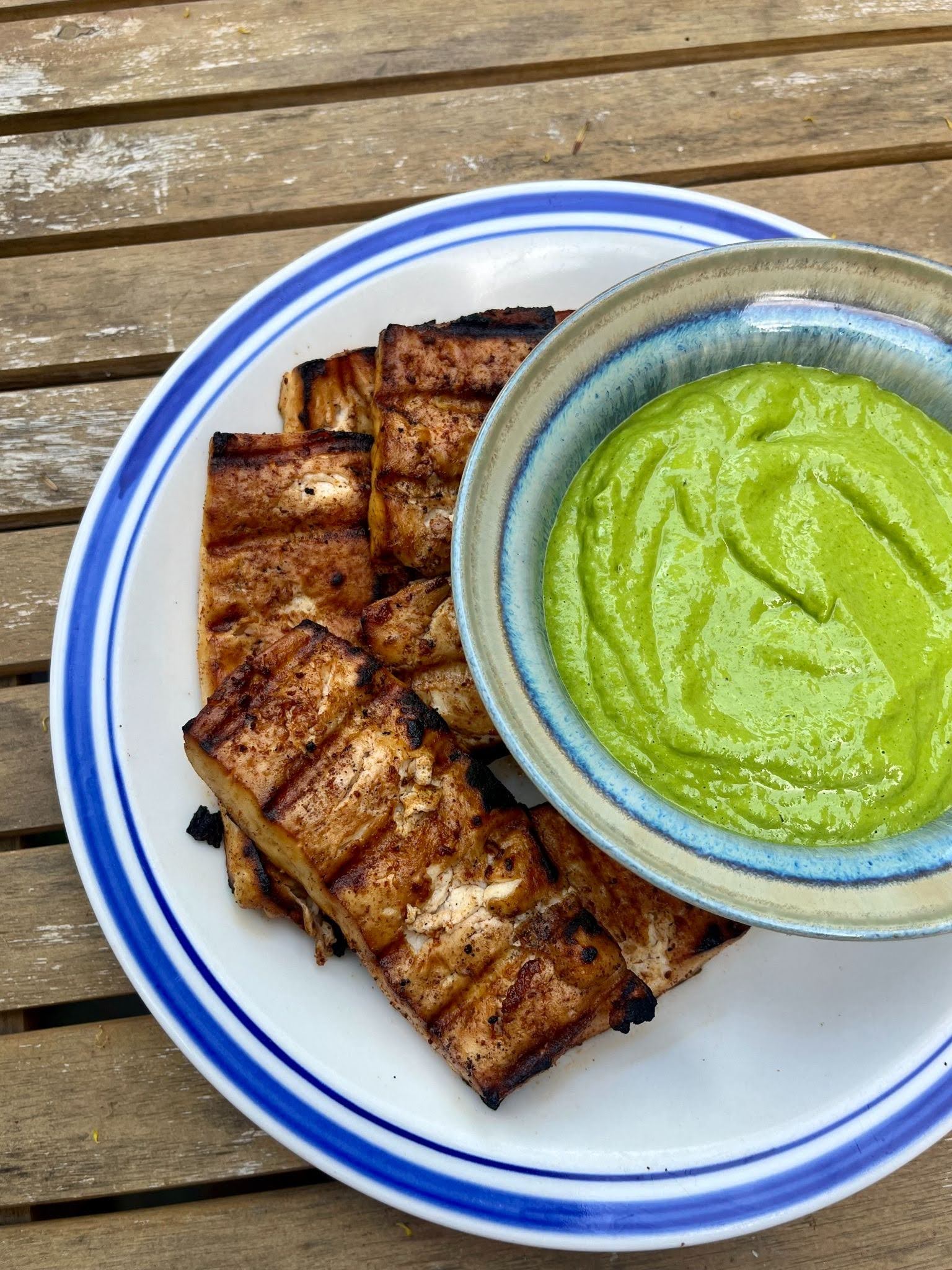 tofu on a white plate with a bowl of sauce on the left side